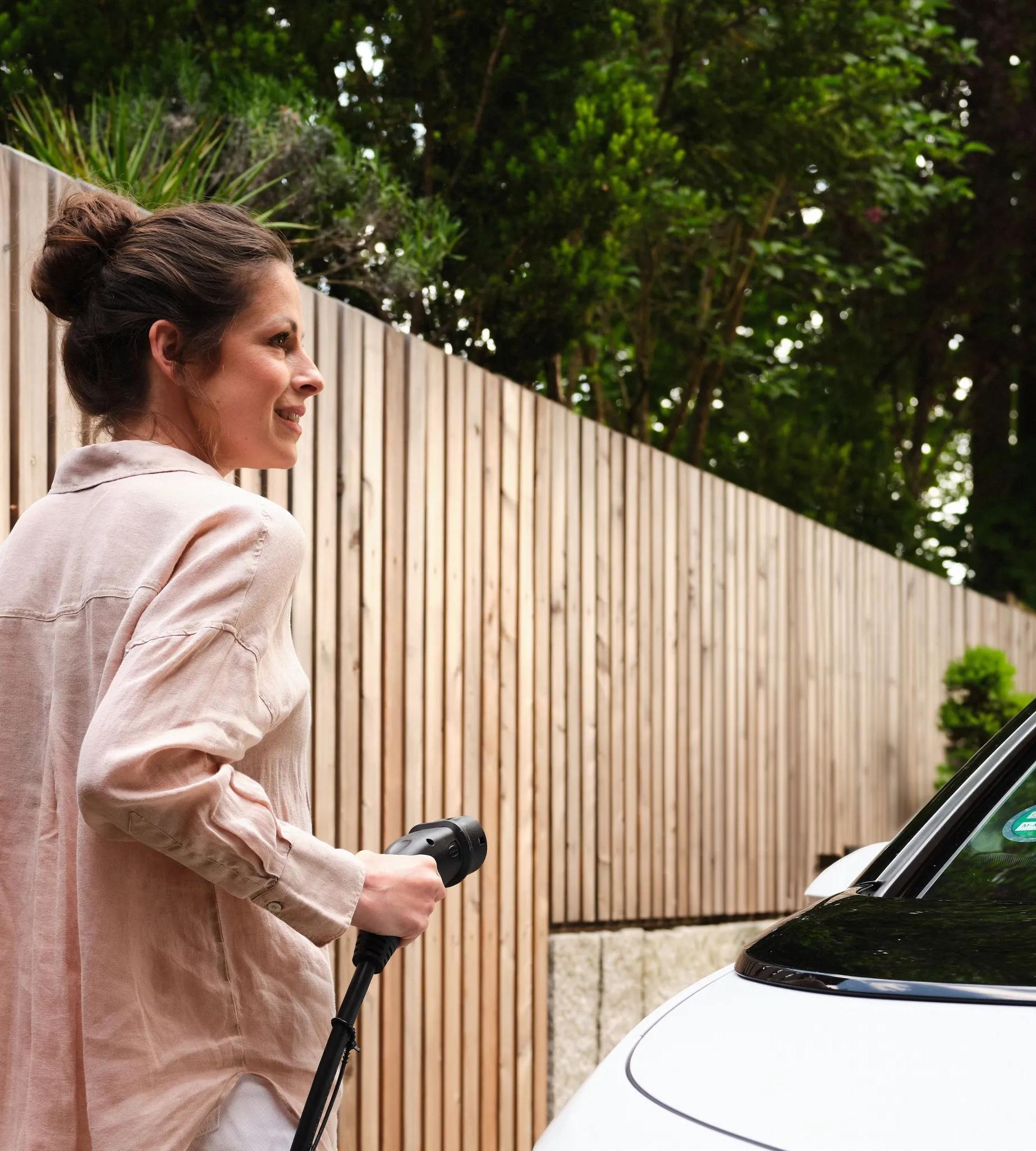 Frau lädt Elektroauto an der Wallbox zuhause