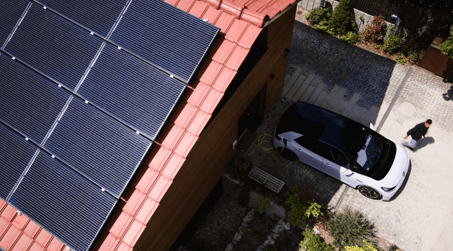 E-Auto in Einfahrt vor einem Haus mit Solaranlage geparkt